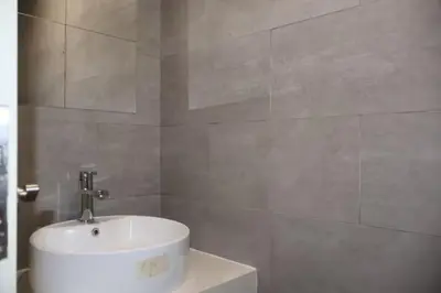 a bathroom with a white sink and a wall at The Colony By Infinitum B in Kuala Lumpur