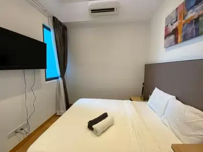 a bedroom with a white bed with a black remote control at The Colony By Infinitum T in Kuala Lumpur