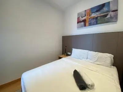 a black object is sitting on a white bed at The Colony By Infinitum T in Kuala Lumpur