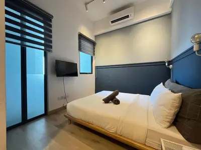 a bedroom with a bed with a blue headboard and a television at The Colony By Infinitum K in Kuala Lumpur