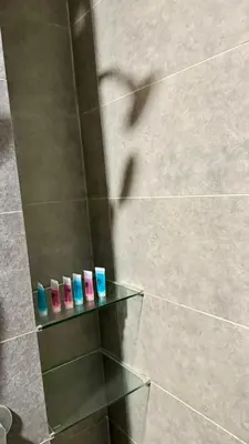 a group of four toothbrushes on a glass shelf in a shower at Comfy 2BR with FREE Parking at Neu Suites by OKBnB in Kuala Lumpur