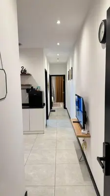 a hallway with white walls and a television on a counter at Comfy 2BR with FREE Parking at Neu Suites by OKBnB in Kuala Lumpur