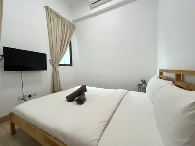 a teddy bear sitting on top of a white bed at The Colony By Infinitum H in Kuala Lumpur