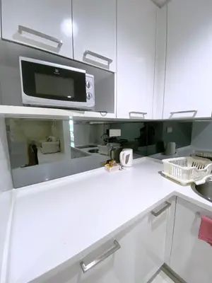a kitchen with white cabinets and a microwave at Mercu Summer Suites Bernice KLCC in Kuala Lumpur