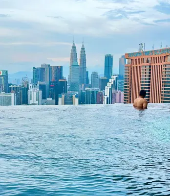 a man sitting in the infinity pool of a building at Lucentia Residence by Infinity swimming pool,lalaport KL in Kuala Lumpur