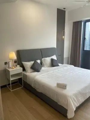 a bedroom with a large bed and a night stand at Modern 1BR Apartment with KLCC Twin Towers View in Kuala Lumpur