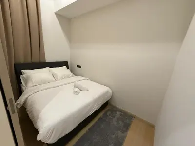 a small bedroom with a bed with white sheets and pillows at Star Residance KLCC by Nexus in Kuala Lumpur