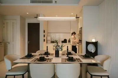 a dining room table with white chairs and a woman in the background at Chic Cityscape Homestay in Bukit Bintang 1-5 people in Kuala Lumpur