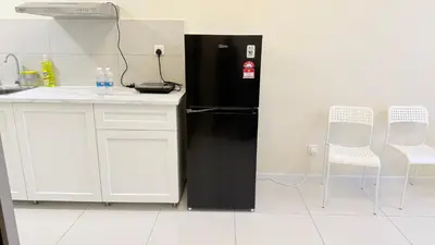 a kitchen with a black refrigerator and two white chairs at majestic Resort Suites KLCC At Bukit bintang in Kuala Lumpur