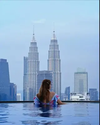 a woman in a infinity pool with a view of the city at The Luminance By Infinitum Haven KLCC in Kuala Lumpur
