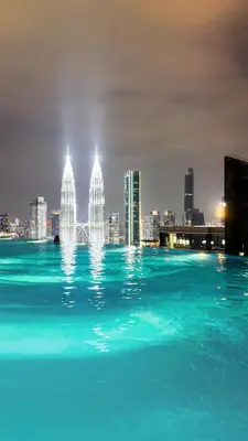 a pool of water with a city skyline at night at Eaton Residence KLCC - J Home in Kuala Lumpur