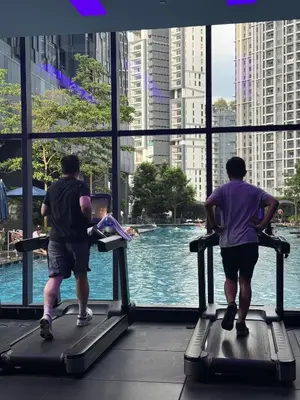 two men running on treadmills in front of a window at Star Residences in Kuala Lumpur