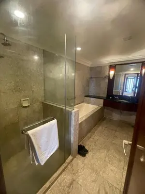 a bathroom with a shower and a tub and a towel at Sunrise Residence At Berjaya Times Square AR in Kuala Lumpur