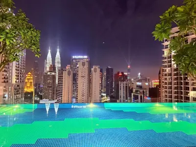a large swimming pool with a city skyline at night at Majestic Suites KLCC by KLIQ in Kuala Lumpur