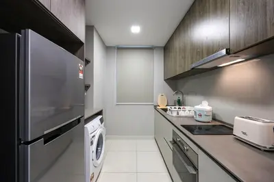 a small kitchen with a washer and dryer in it at Elegant Skyline Suite Datum Jelatek near KLCC in Kampong Datok Keramat