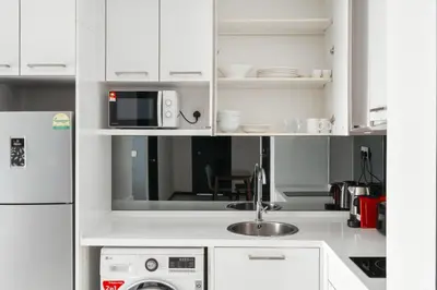 a white kitchen with a sink and a microwave at Blueground Kampung Baru pool nr KL Tower KUL-9 in Kuala Lumpur