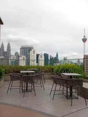 a patio with tables and chairs and a city skyline at Majestic Residence Kuala Lumpur in Kuala Lumpur