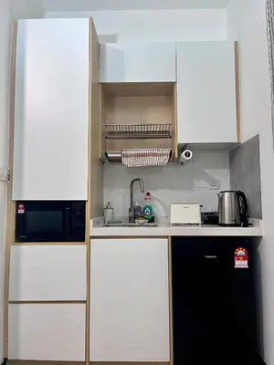a kitchen with white cabinets and a black refrigerator at Comfort Stay Neusuite Jelatek in Kuala Lumpur