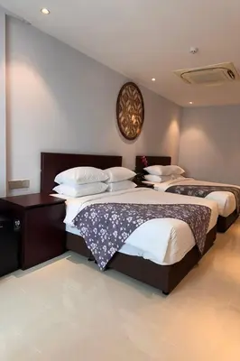 a bedroom with two beds and a clock on the wall at Lofts At Hang Kasturi Kuala Lumpur in Kuala Lumpur