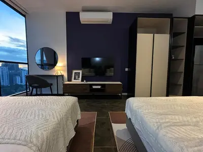 a bedroom with two beds and a tv and a desk at Scarletz Suites KLCC Studio in Kuala Lumpur