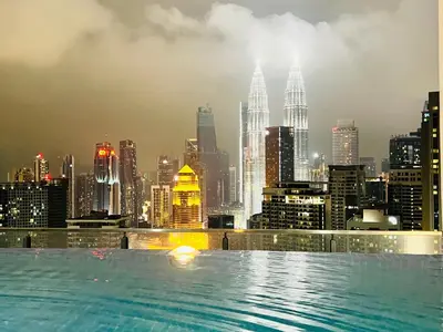 a swimming pool with a city skyline in the background at The Luxe Infinity Skypool By Tasu Homes in Kuala Lumpur