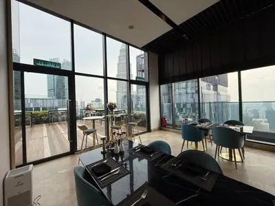 a room with a table and chairs and large windows at Star Residance KLCC by Nexus 13 in Kuala Lumpur