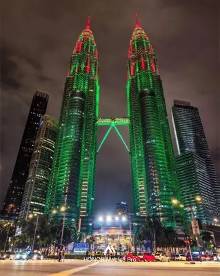 two tall buildings are lit up green at night at Star Residance KLCC by Nexus 13 in Kuala Lumpur