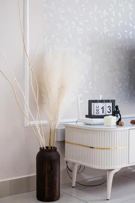 a clock sitting next to a table with a feather in a vase at Cozy Home to explore KL City KLCC TRX Bkt Bintang in Kuala Lumpur