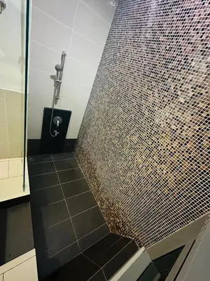 a bathroom with a shower with a brown tiled wall at Swiss Garden Resident By FA in Kuala Lumpur