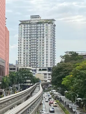 a large white building with cars on a city street at KLCC View Apartment in Kuala Lumpur