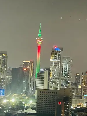 a city skyline with a lit up tower in the city at KLCC View Apartment in Kuala Lumpur