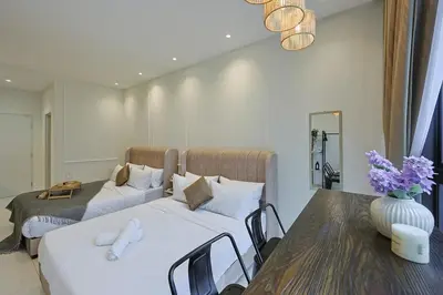 a bedroom with two beds and a table and a vase with flowers at Majestic Residence near KLCC Quill City 2 in Kuala Lumpur