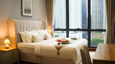 a bedroom with a large white bed with a large window at Manor Residences KLCC in Kuala Lumpur