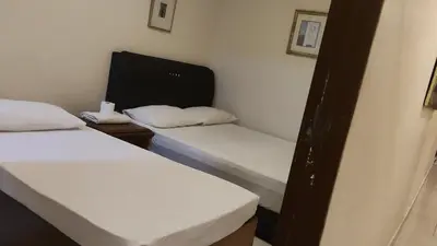 two beds in a small room with white sheets at HOTEL NoVA in Kuala Lumpur