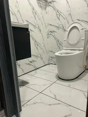 a bathroom with a white toilet and marble walls at KING HOSTEL by Global Inn in Kuala Lumpur