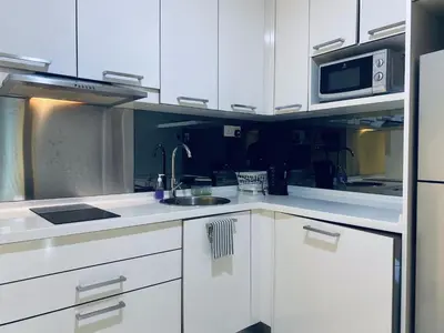 a kitchen with white cabinets and a sink and a microwave at Summer Suites KLCC by Vho'Z in Kuala Lumpur