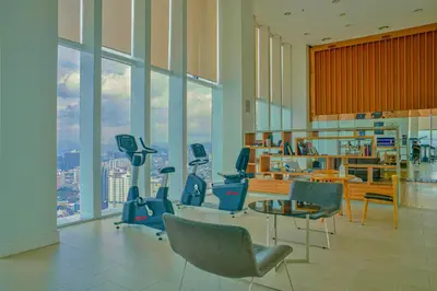 a gym with chairs and a table and windows at Aura Suites at Platinum KLCC in Kuala Lumpur