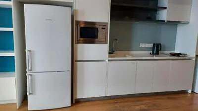 a kitchen with white cabinets and a microwave and a refrigerator at Aura Suites at Platinum KLCC in Kuala Lumpur