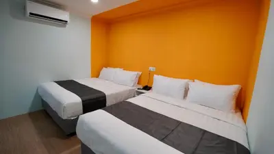 two beds in a hotel room with orange walls at Alami Garden Hotel Kuala Lumpur in Kuala Lumpur