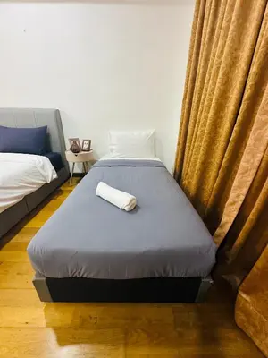 a bedroom with a bed and a couch and curtains at Regalia Apartments By FA 3 in Kuala Lumpur
