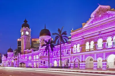 a building covered in purple lights with a clock tower at High-Floor Suasana KL Stay Cozy & Central in Kuala Lumpur