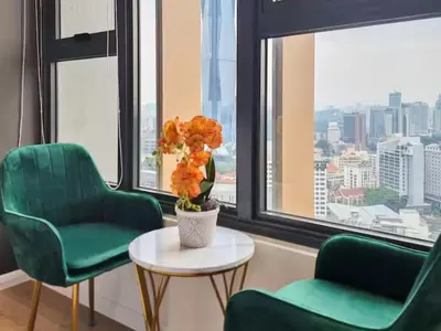 a room with two green chairs and a table with flowers at KL City Designer Studio in Ceylonz with KL118 Tower View CityNest in Kuala Lumpur