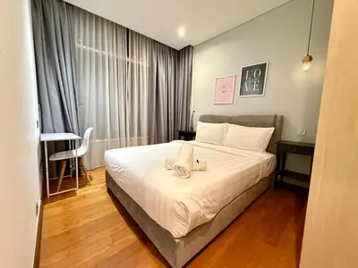 a bedroom with a bed with white sheets and a table at Apartment KL Luxury Home Stay in Kuala Lumpur