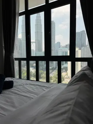 a bed in front of a window with a city view at Legasi Residence Direct KLCC VIEW Only10minWalkToKLCC With PS4 AndBoardGames in Kuala Lumpur