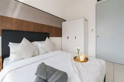 a bedroom with a white bed with a wooden headboard at Luxury 3Bedroom Kenwingston Platz 15Mins To KLCC Fit 9Pax A15 in Kuala Lumpur