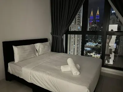 a bedroom with a bed with white sheets and a window at Majestic Residence KLCC By MYHOME in Kuala Lumpur