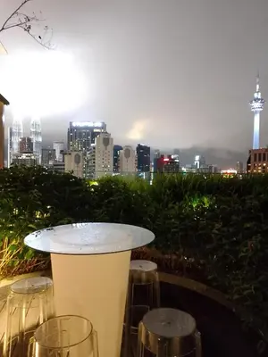 a table and stools with a view of the city at majestic residence klcc rooftop pool in Kuala Lumpur