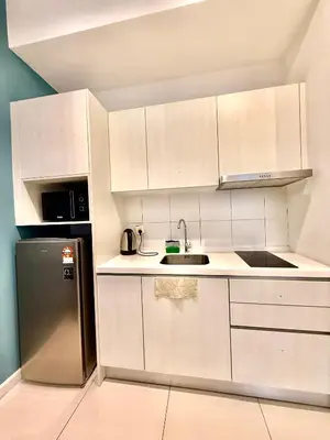 a kitchen with white cabinets and a stainless steel refrigerator at Klcc Suites 1 By Chambers RMS in Kuala Lumpur