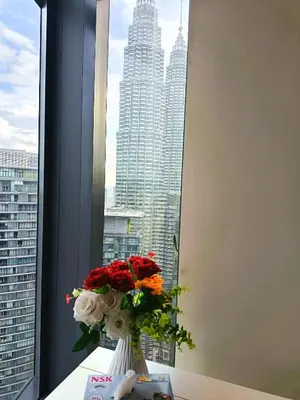 a vase of flowers sitting on a table in a window at Rahmans Care At Star Residence KLCC in Kuala Lumpur