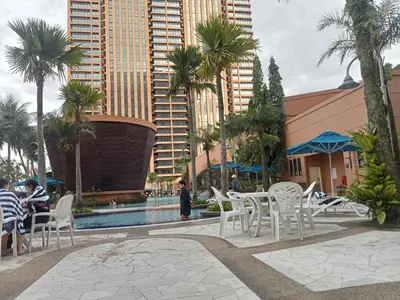 a pool with white chairs and palm trees and buildings at Arba Suite Times Square KL in Kuala Lumpur